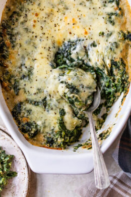 Spinach Gratin in a casserole dish with a serving spoon.